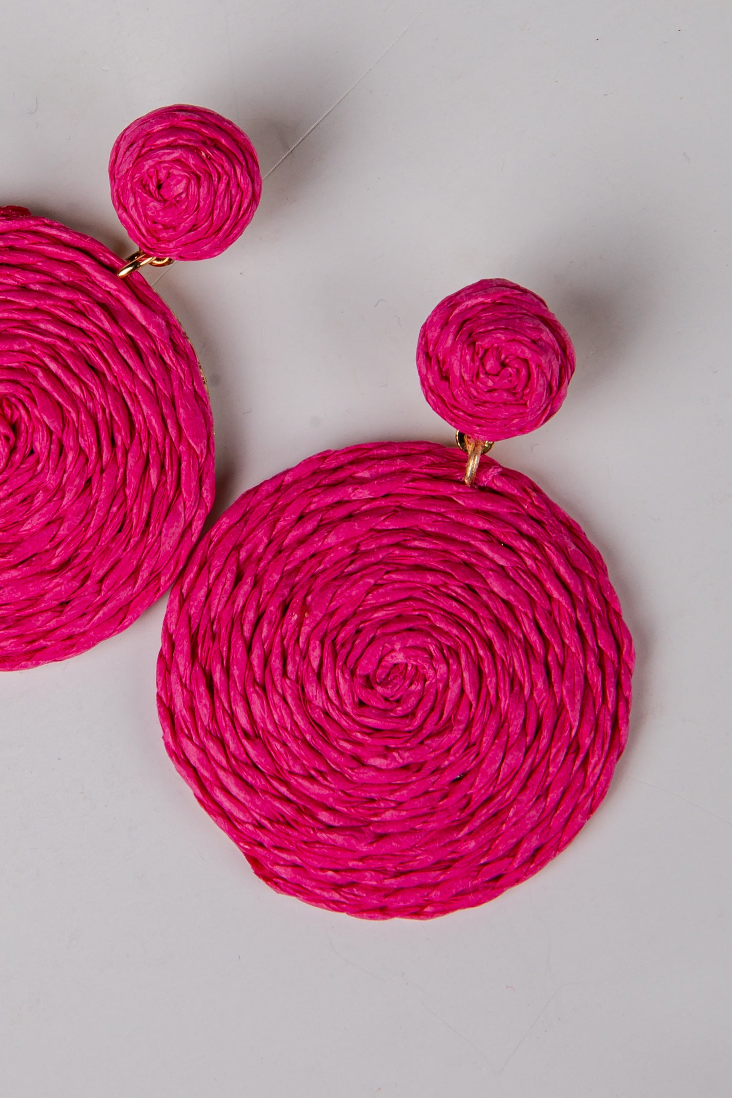 Pink woven earrings on a light gray background