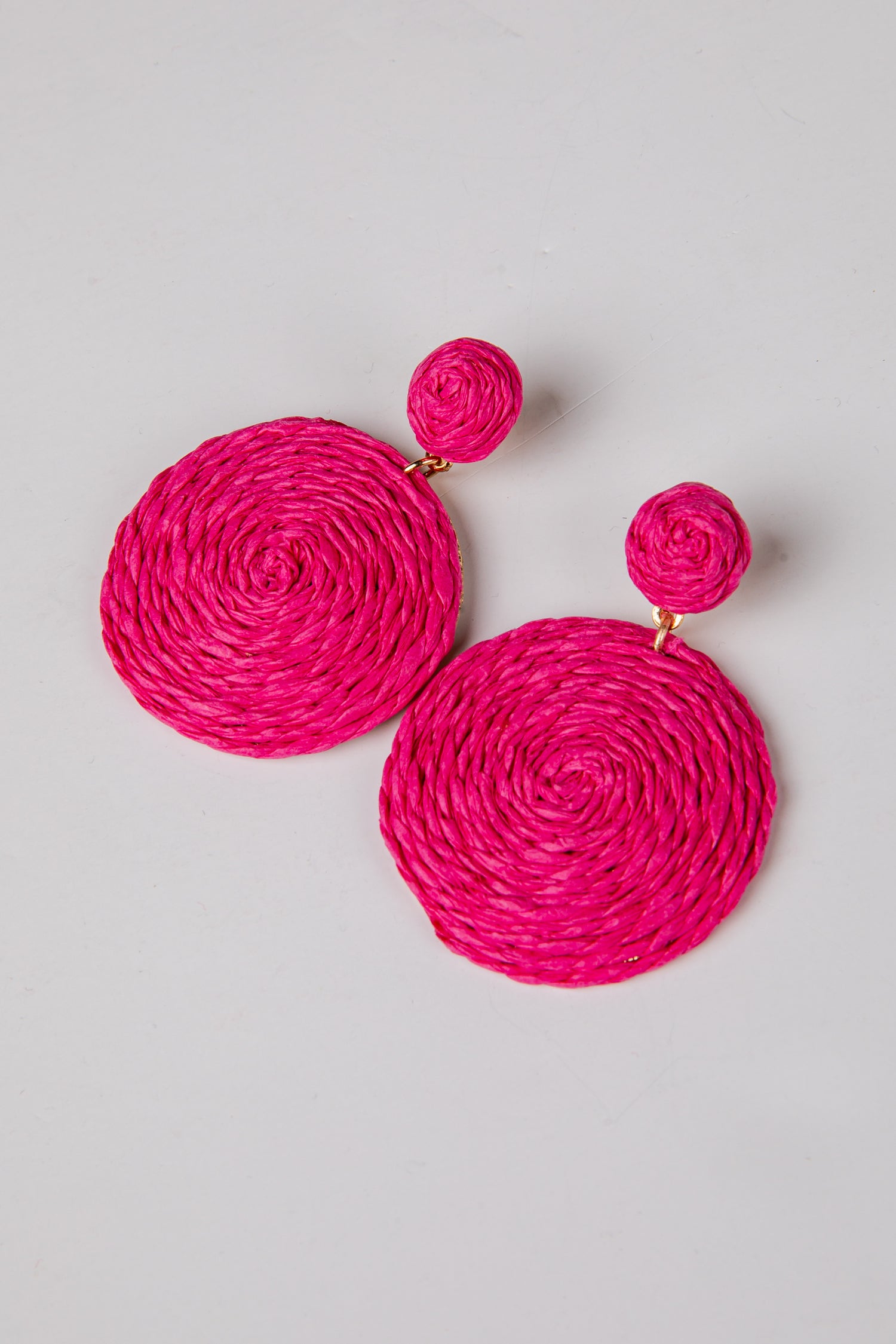 Pair of bright pink earrings on a light gray background