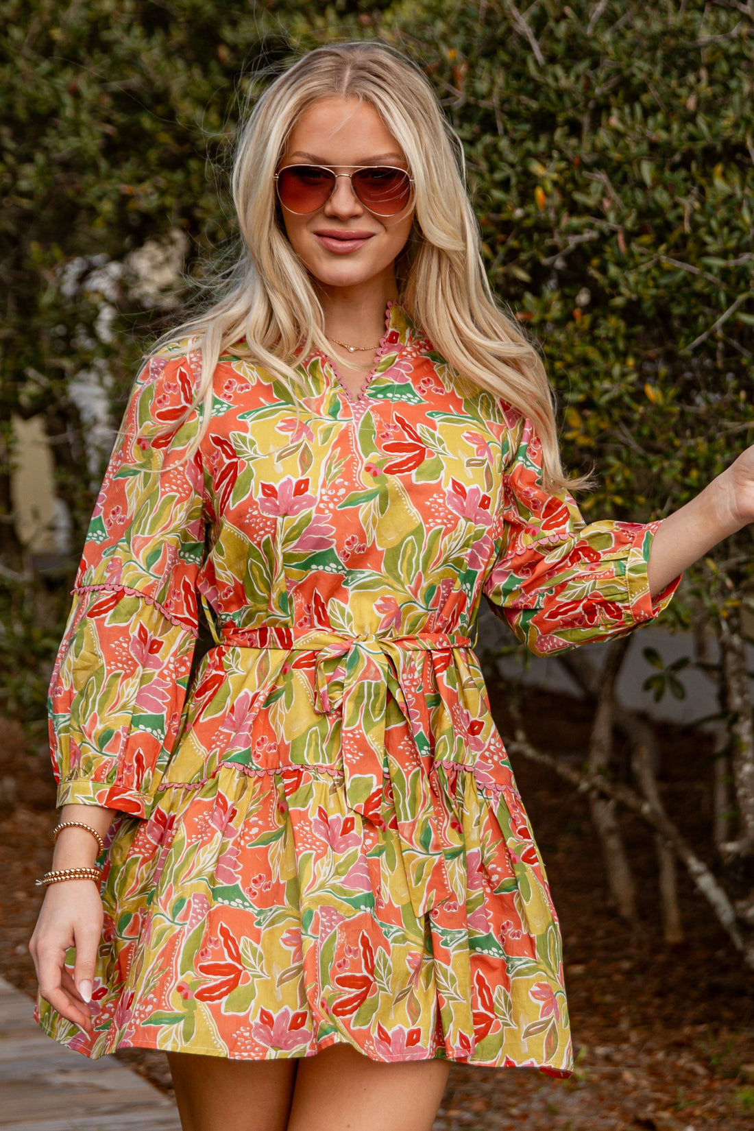 Woman wearing a colorful floral dress walking outdoors.