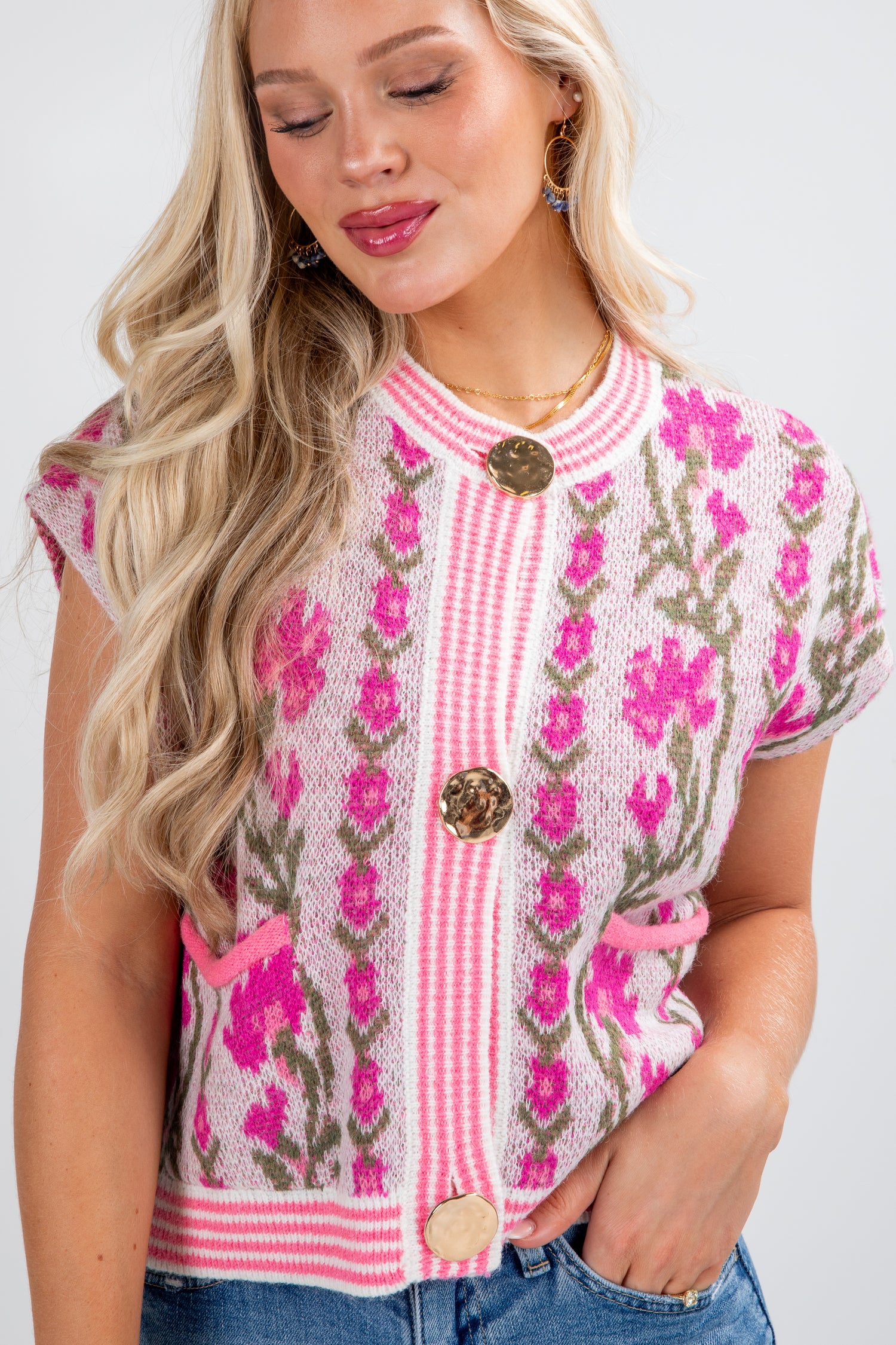 Woman wearing a pink floral embroidered top with buttons on a white background