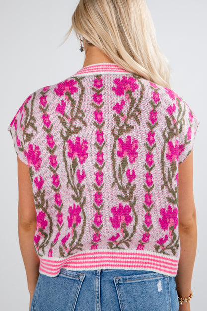 Person wearing a pink floral patterned vest on a plain background