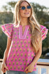 Woman wearing a pink blouse with ruffled sleeves and sunglasses, standing outdoors.