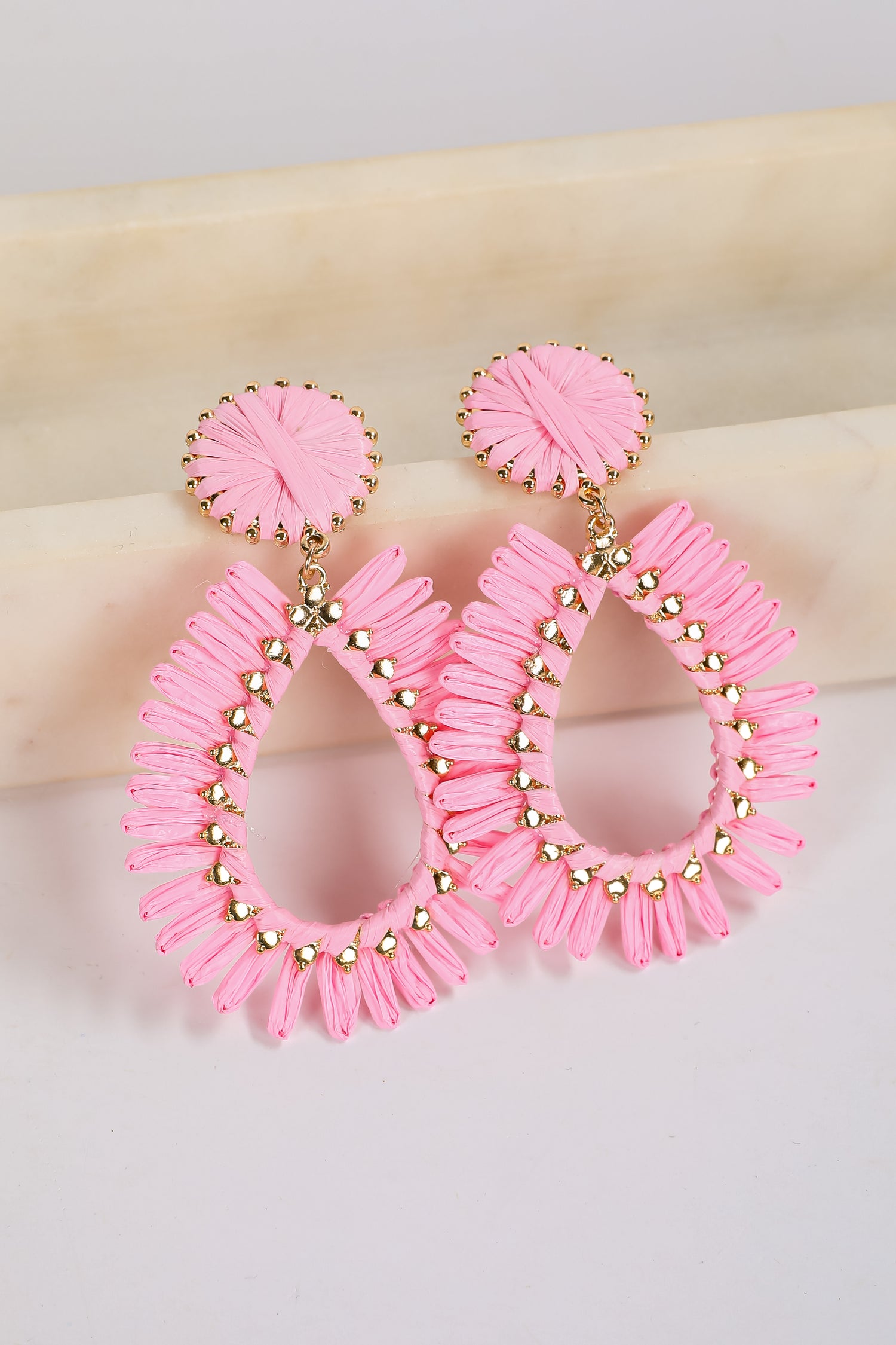 Pink hoop earrings with gold accents on a light background