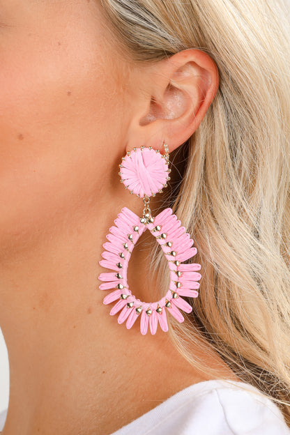 Close-up of a person wearing pink hoop earrings with a blurred background