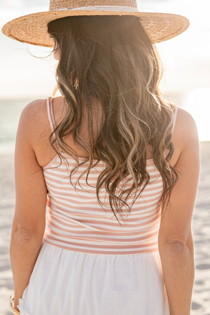 Woman wearing a striped tank top and straw hat on a beach