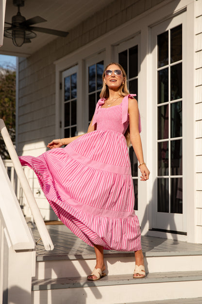 Woman in a pink dress standing on a porch