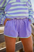 Person wearing a striped shirt and purple shorts with a blurred background