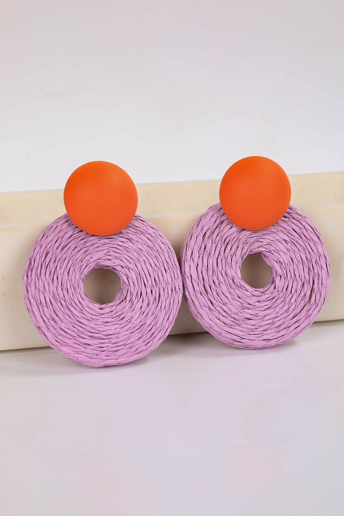 Pair of earrings with purple circular designs and orange accents on a white background