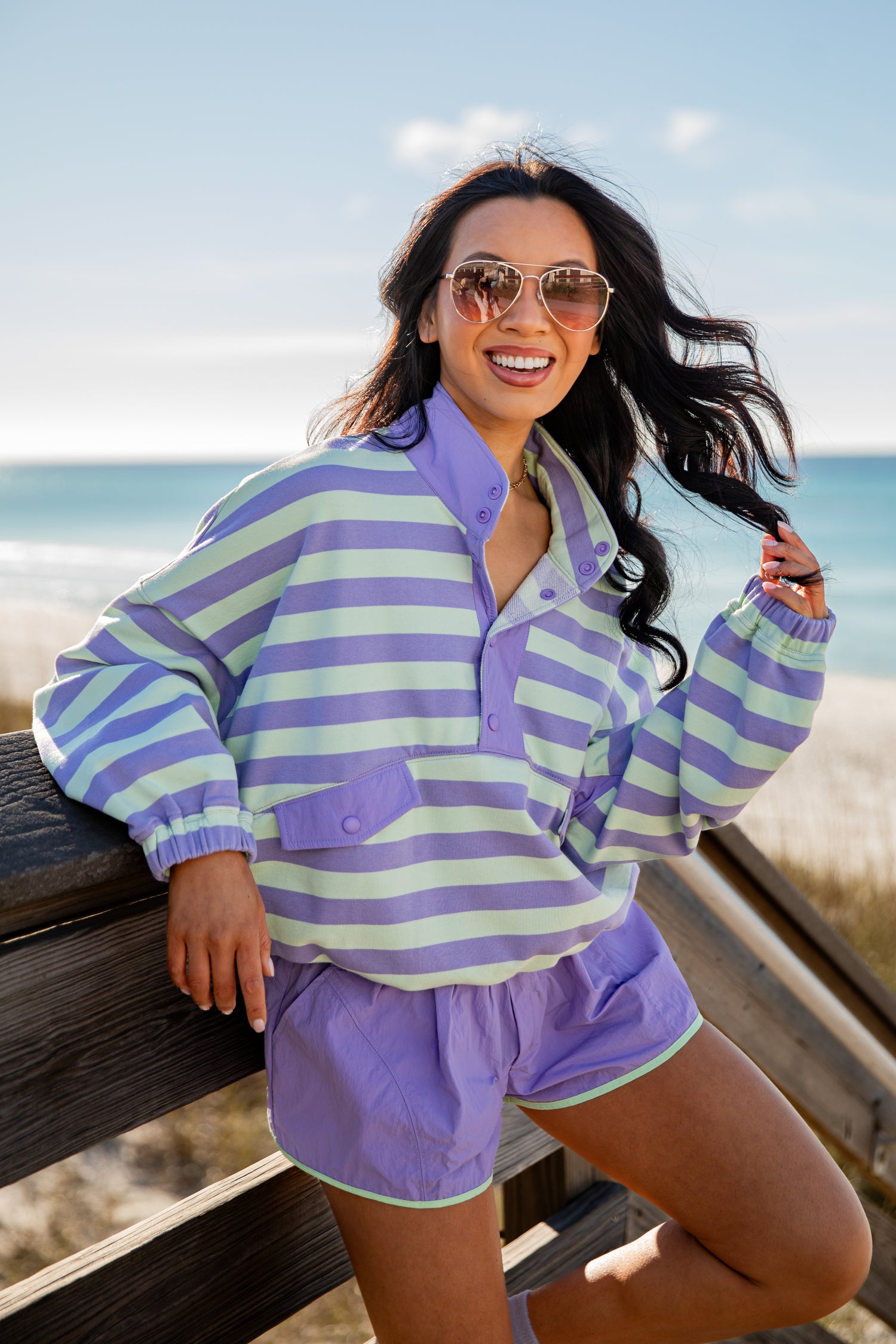 Woman wearing a striped shirt and shorts by the beach