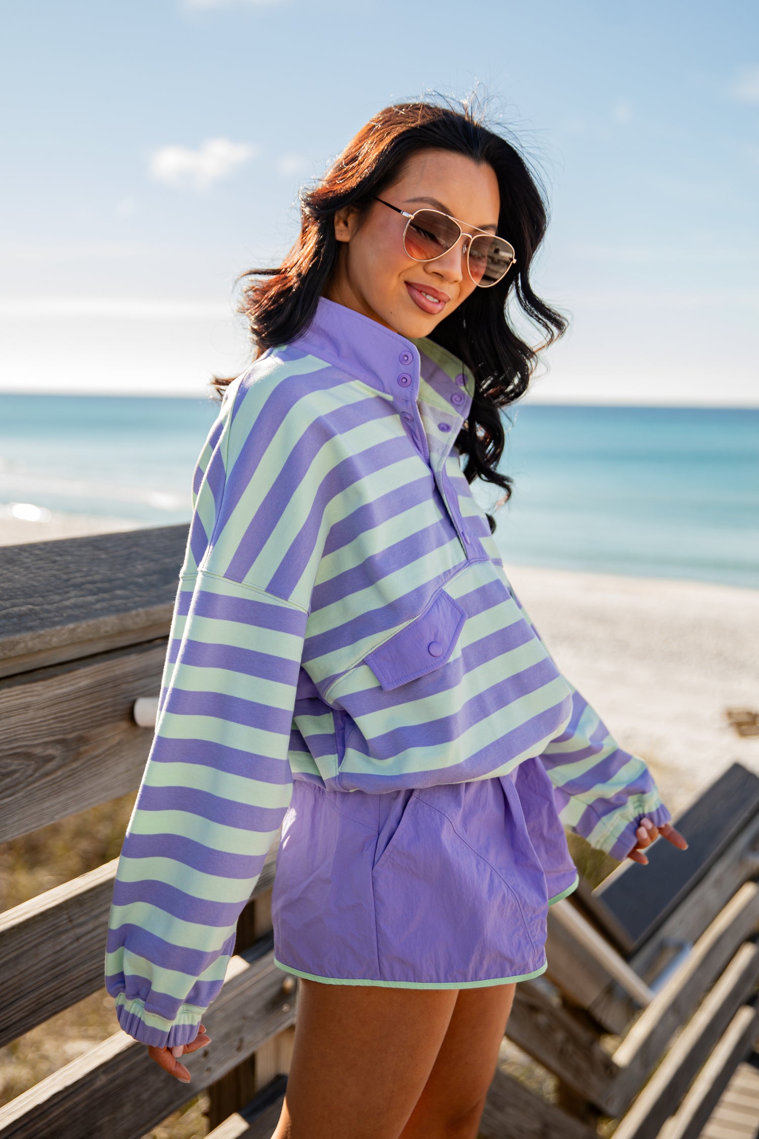 Woman wearing a striped shirt and shorts by the beach