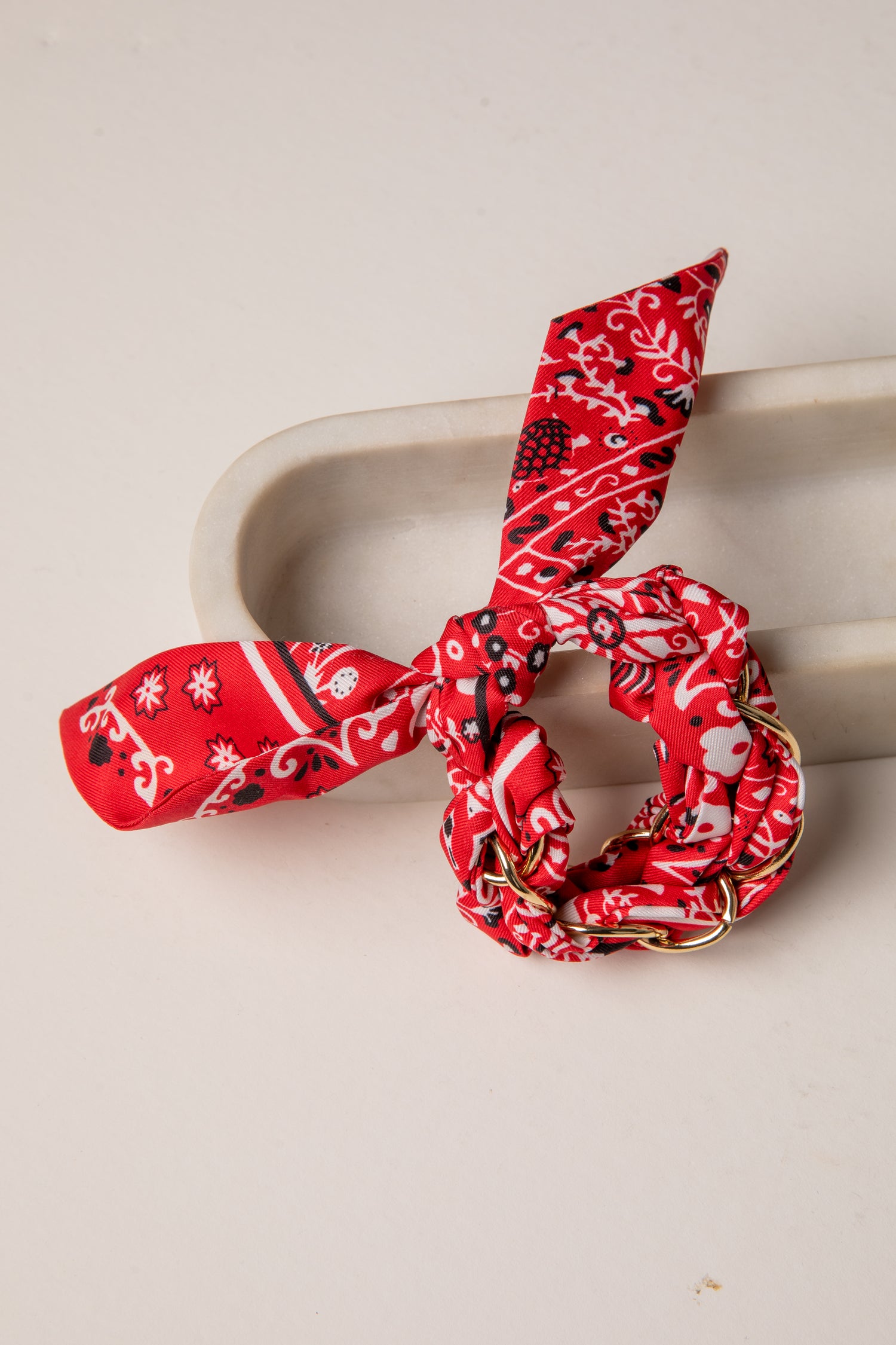 Red patterned hair scrunchie on a beige surface
