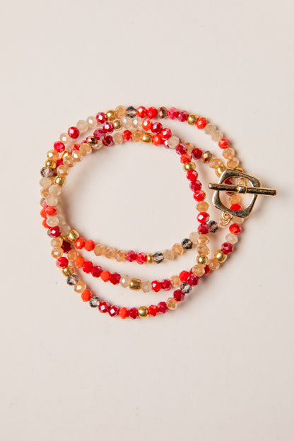 Multicolored beaded necklace with a gold clasp on a light beige background