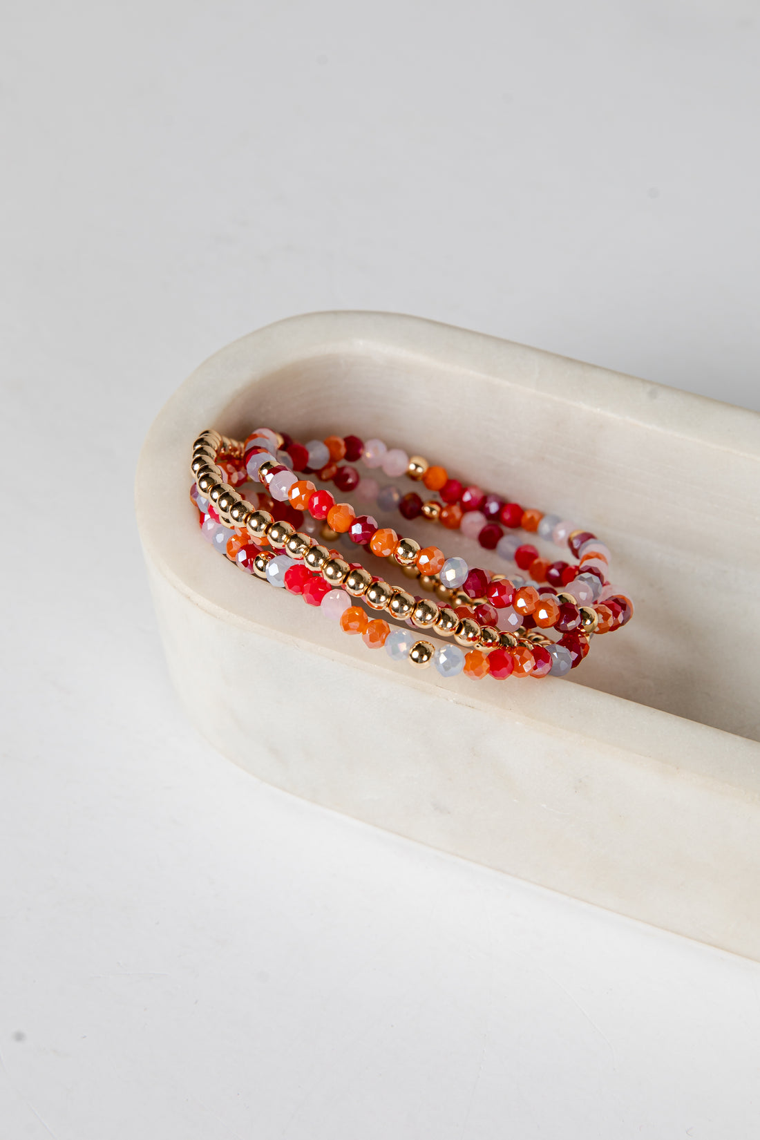 Set of beaded bracelets on a white dish with a white background