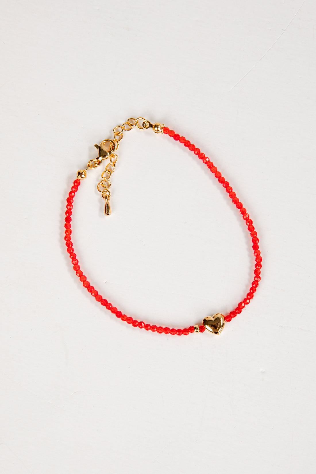 Red beaded bracelet with gold accents on a white background