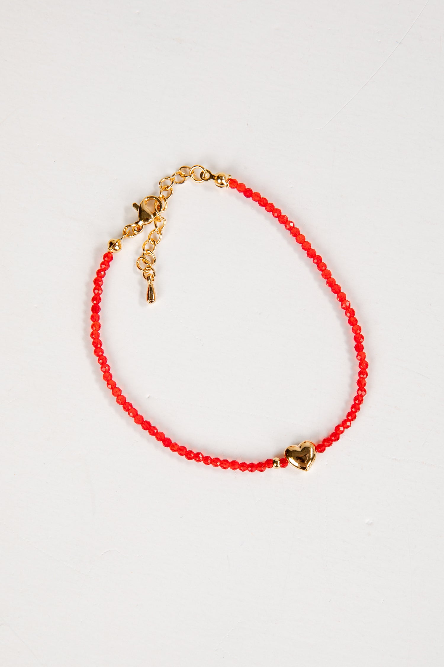 Red beaded bracelet with gold accents on a white background