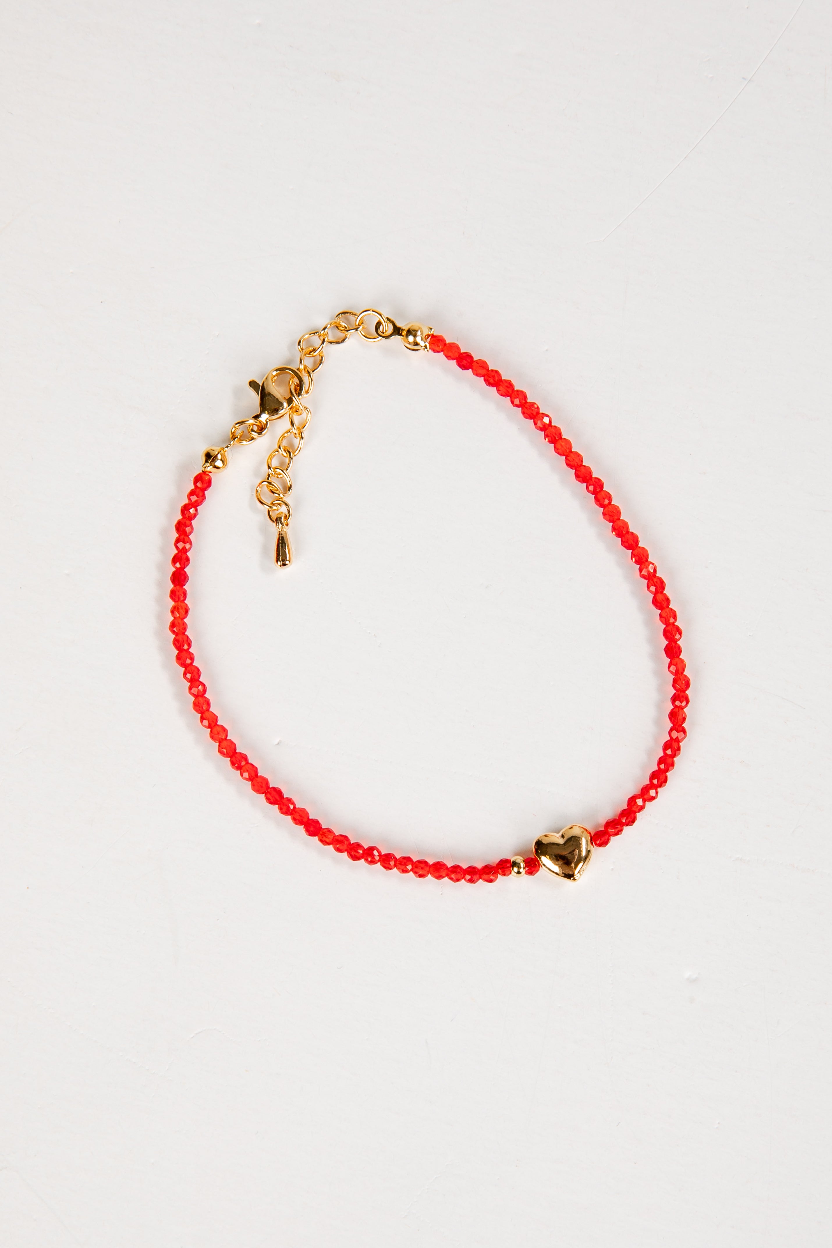 Red beaded bracelet with gold accents on a white background