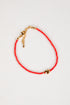 Red beaded bracelet with gold accents on a white background
