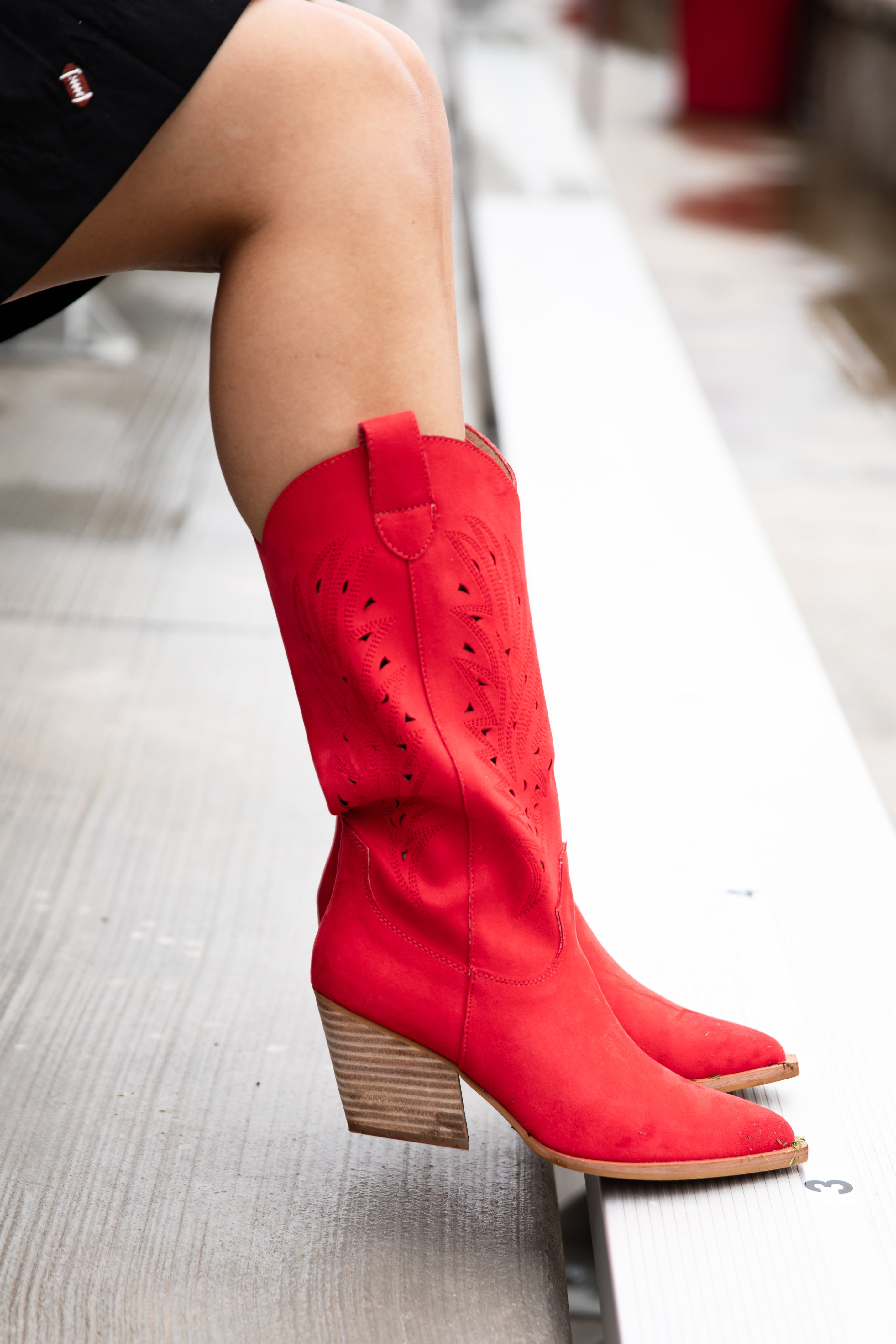 Red knee-high boots with cut-out design on a light gray floor.