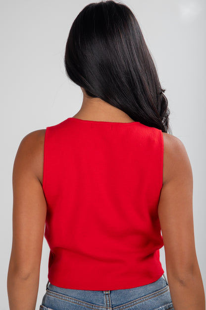 Person wearing a red sleeveless top and blue jeans on a plain background