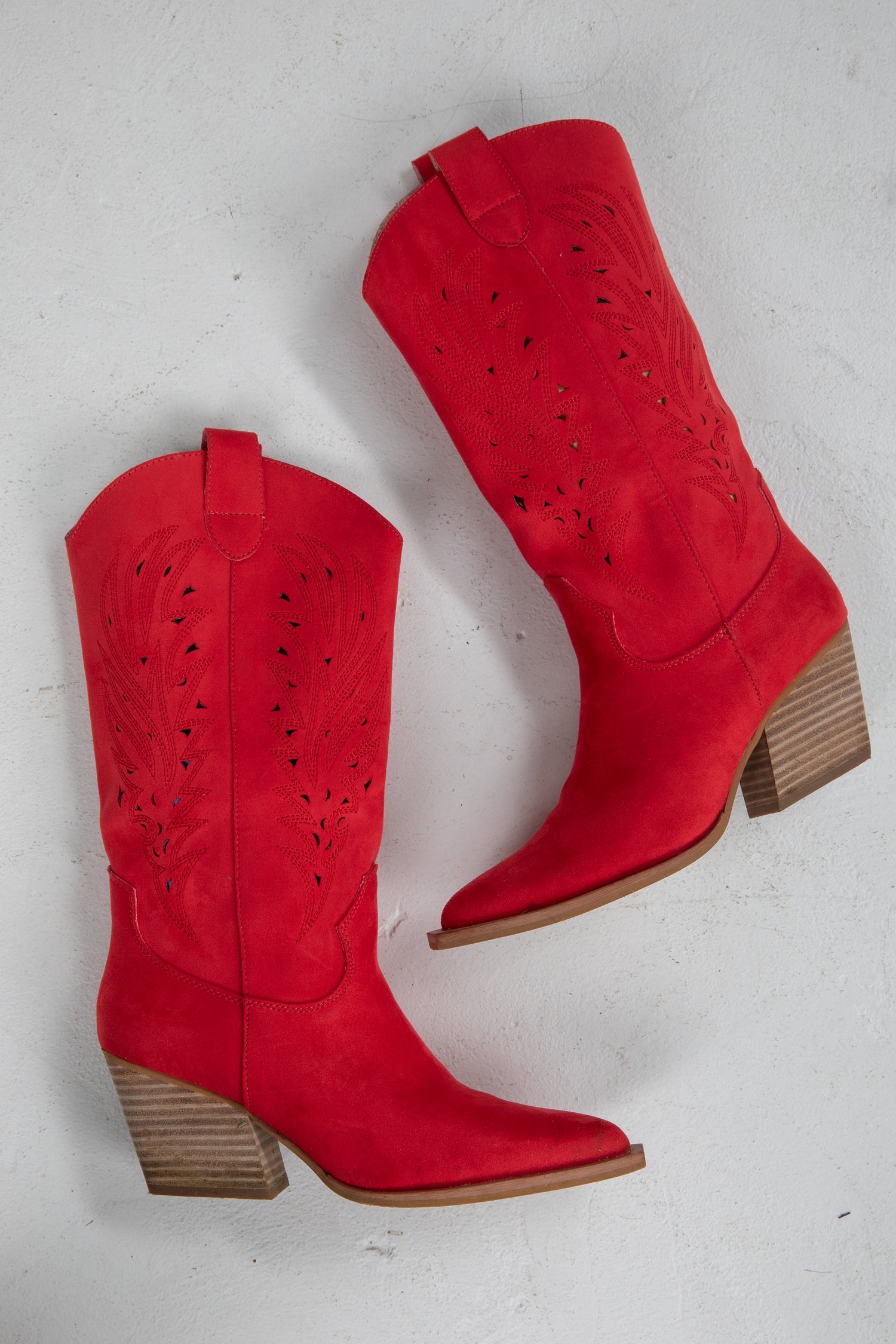 Red cowboy boots with brown soles on a light gray background