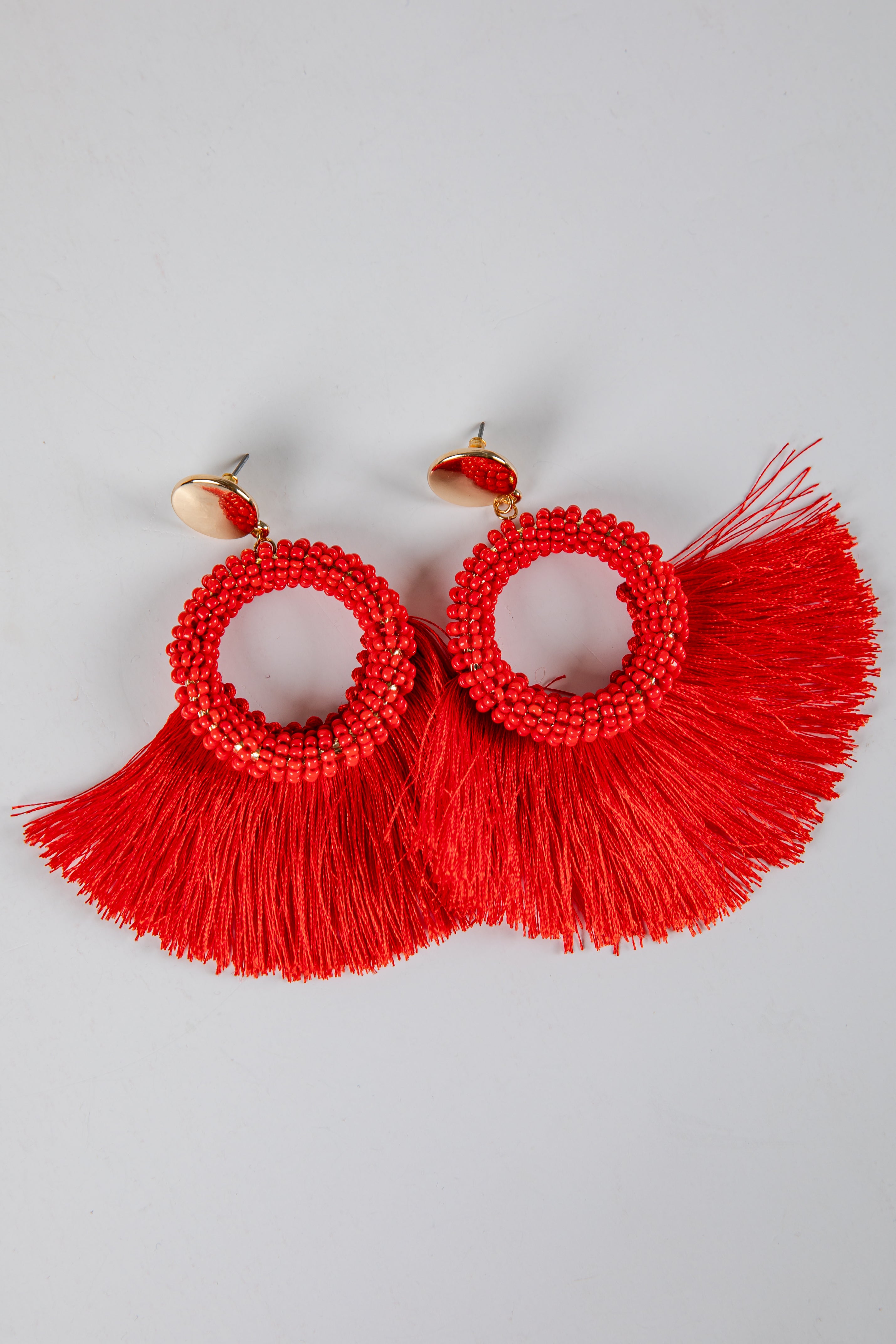 Red tassel earrings on a light gray background