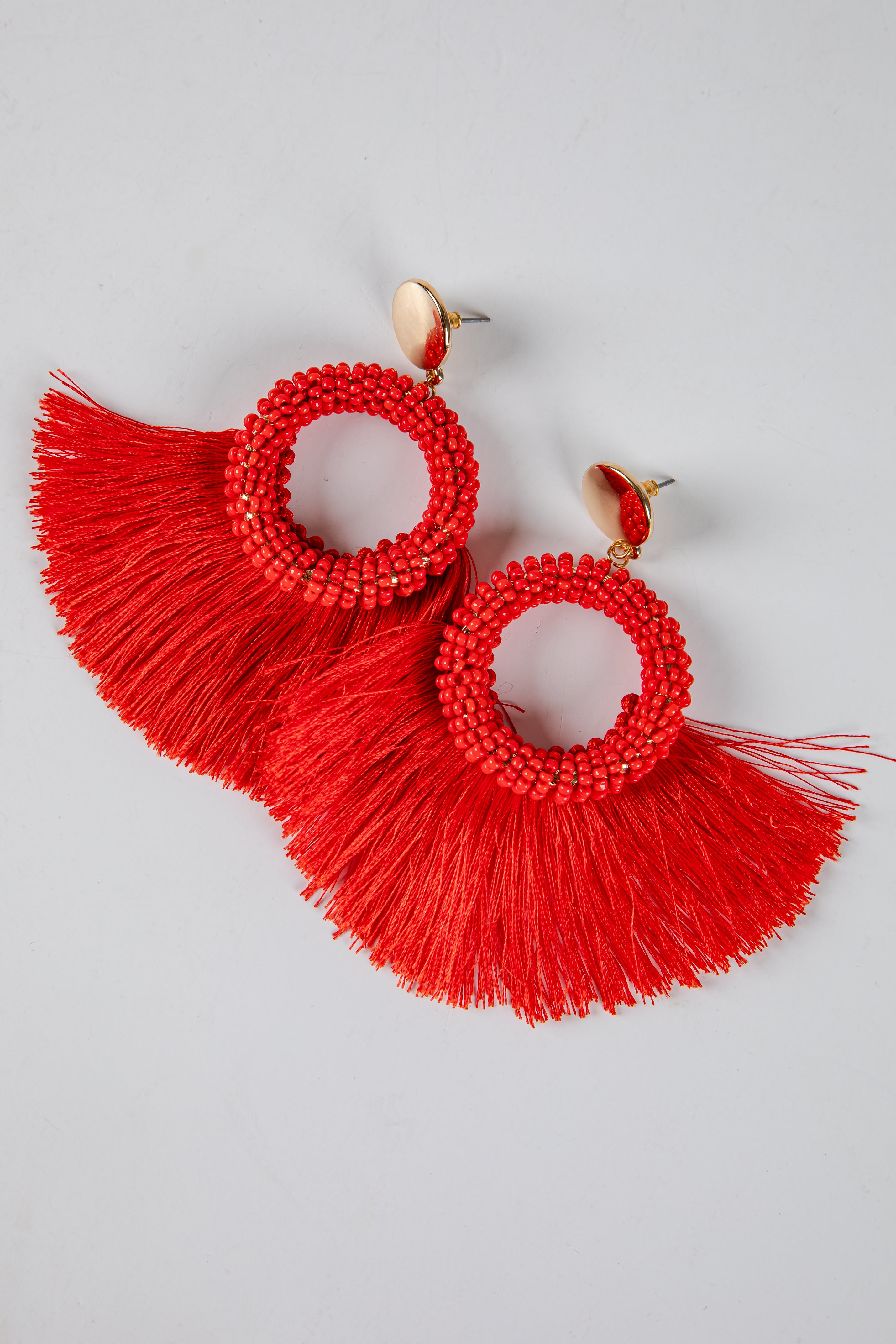 Red tassel earrings on a light gray background