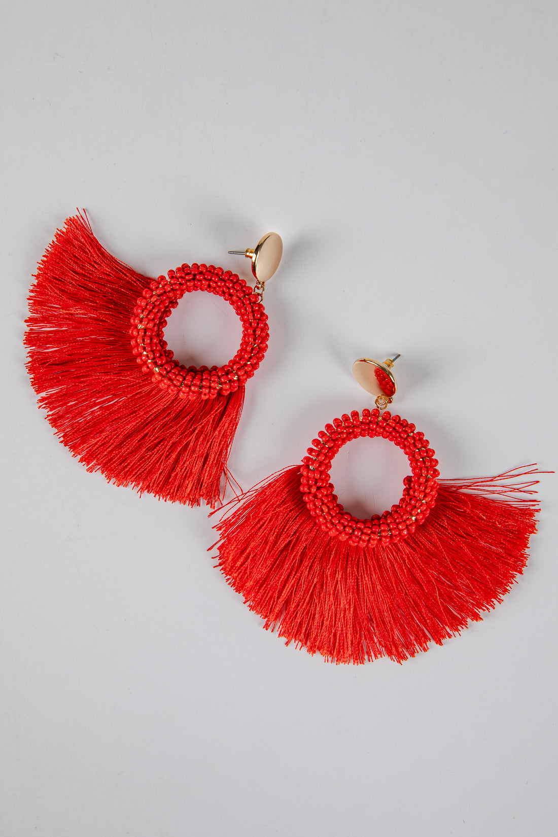 Red fringe earrings on a gray background