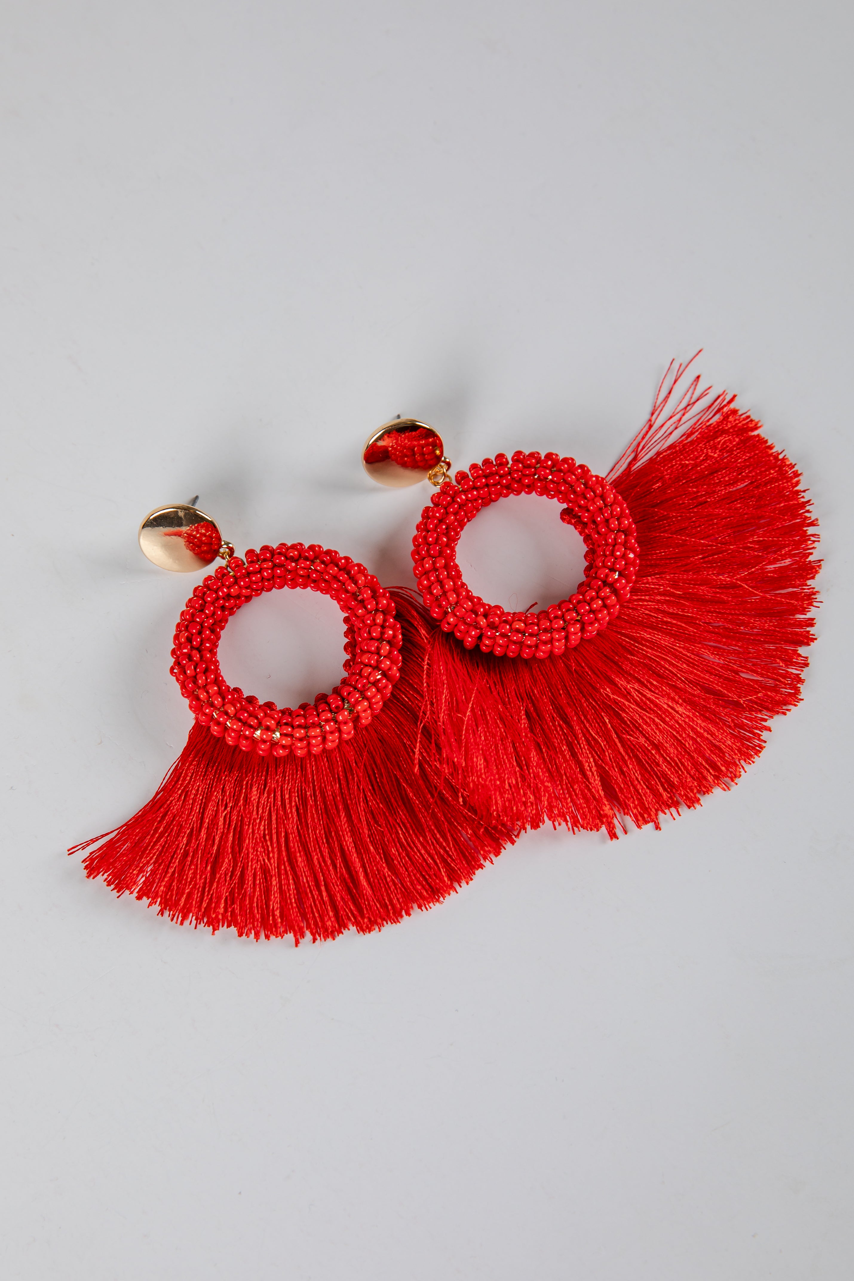 Red tassel earrings on a light gray background