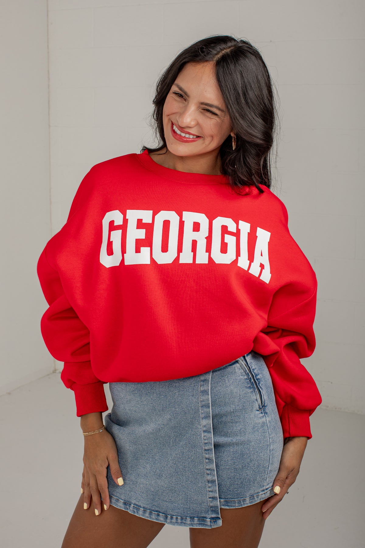 A woman wearing a bright red oversized sweatshirt with &