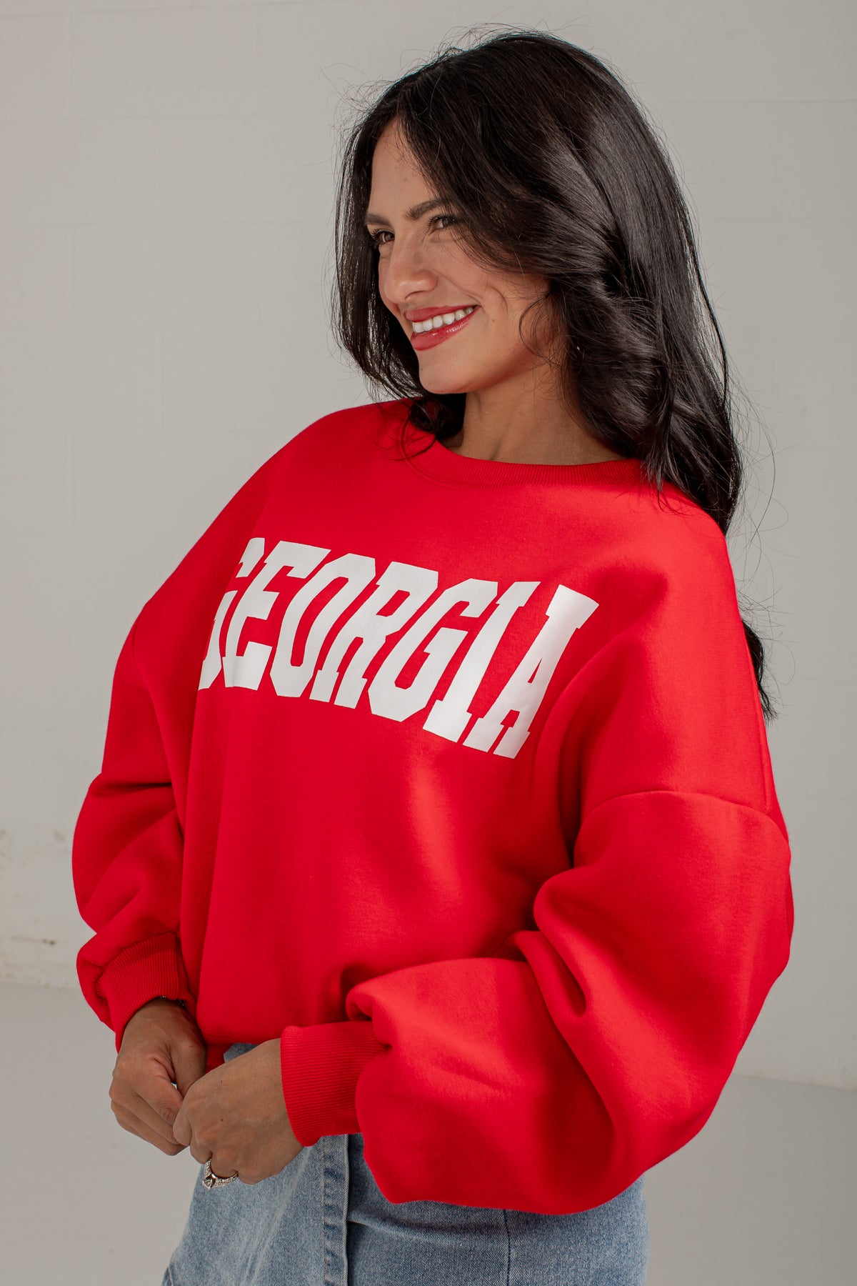 A woman wearing a bright red crewneck sweatshirt with &