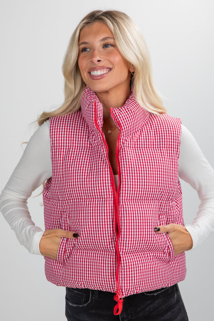 Woman wearing a red checkered puffer vest on a white background