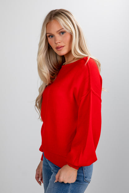 Woman wearing a red sweater and blue jeans on a white background