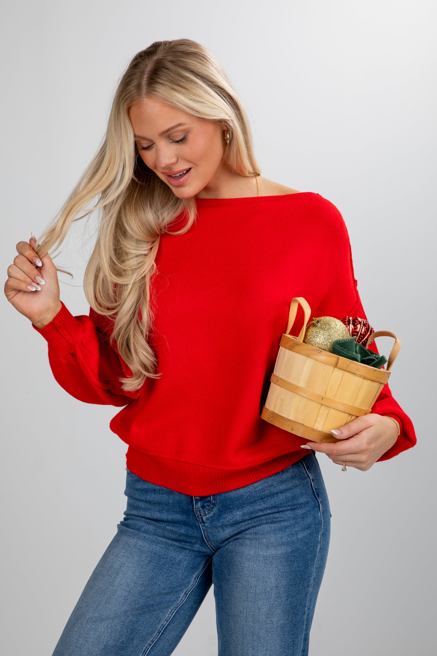 Woman in a red sweater holding a wooden basket with a white background