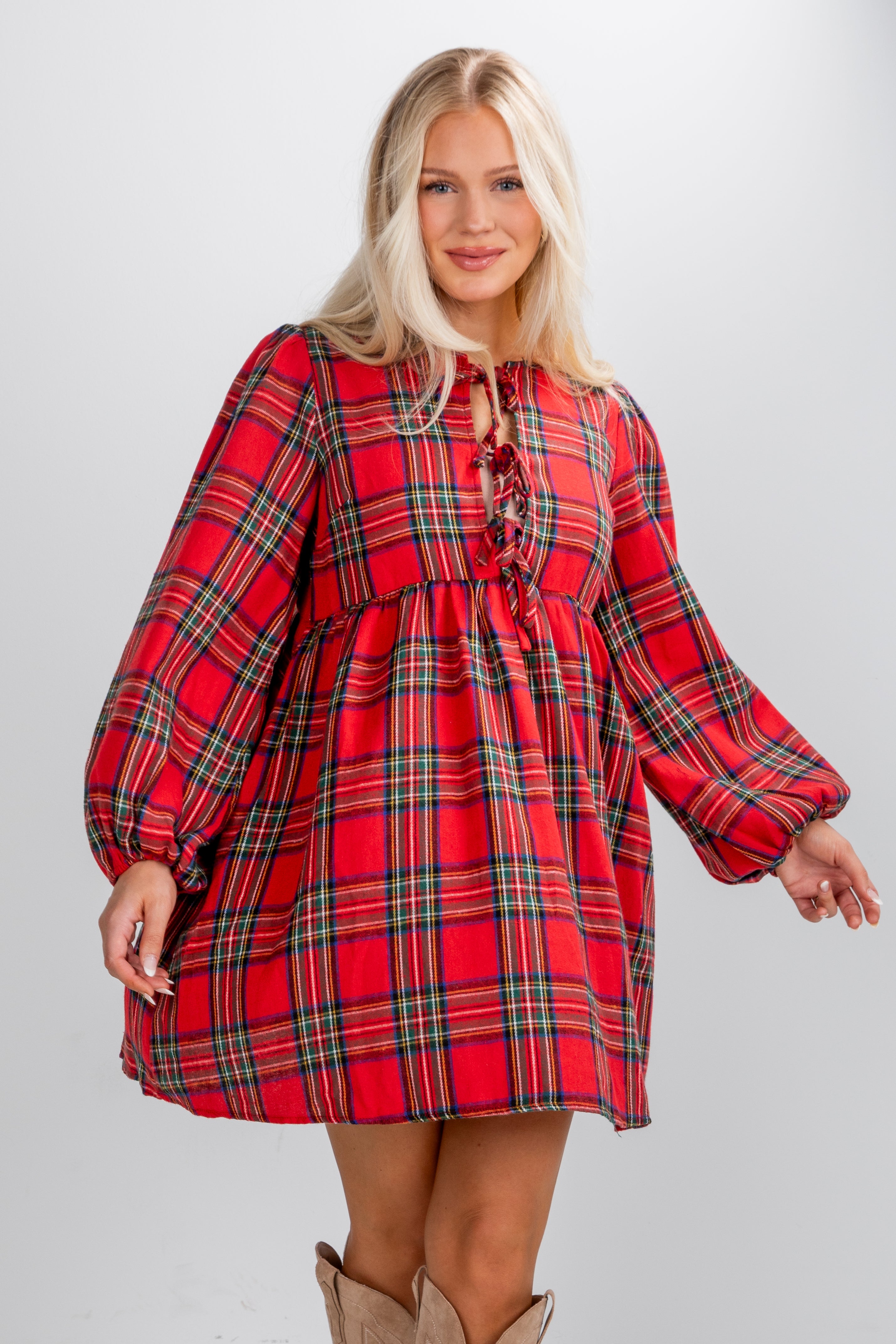 Woman wearing a red plaid dress with long sleeves on a plain background