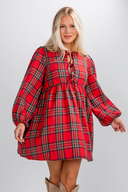 Woman wearing a red plaid dress with long sleeves on a plain background