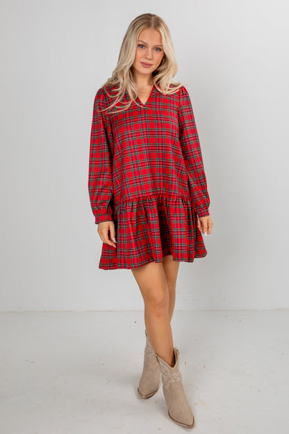 Woman wearing a red plaid dress with long sleeves on a white background