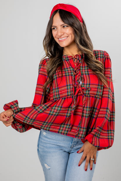 Woman wearing a red plaid blouse and blue jeans against a gray background