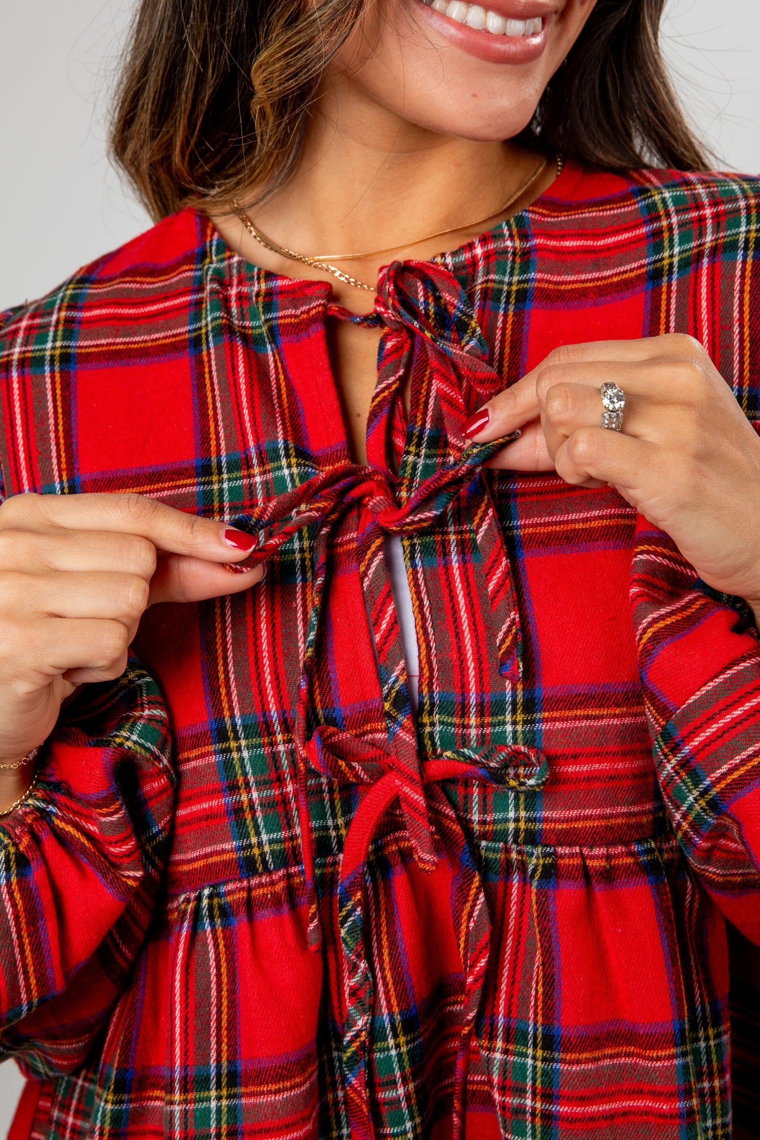 Woman wearing a red plaid dress pointing to the fabric