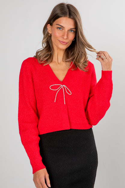Woman wearing a red sweater with a white bow design on a gray background