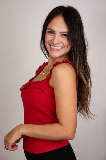 Woman wearing a red top with ruffled details against a plain background