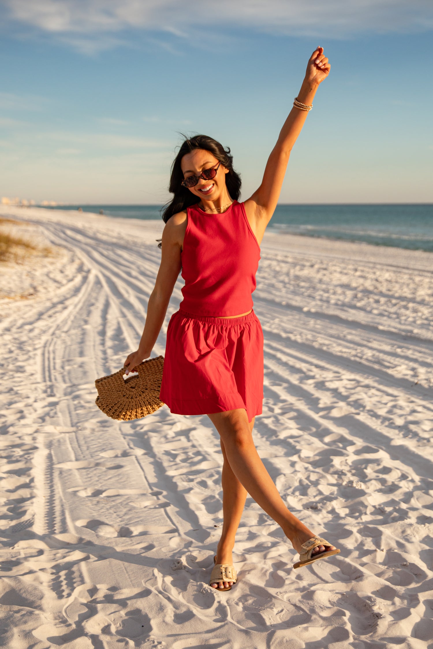 Woman in a red dress on a sandy beach with ocean and sky in the background