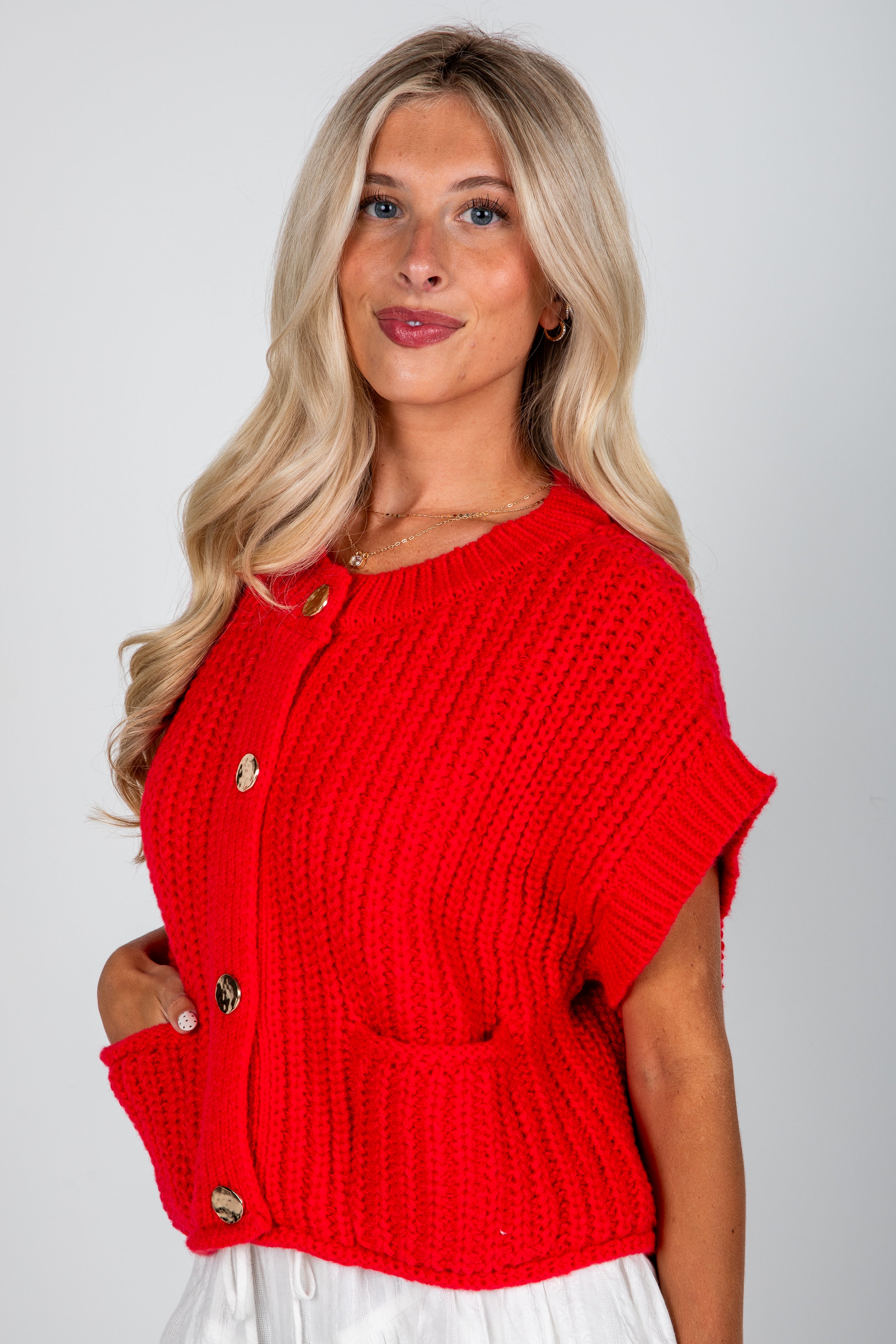 Woman wearing a red knitted cardigan with a plain background