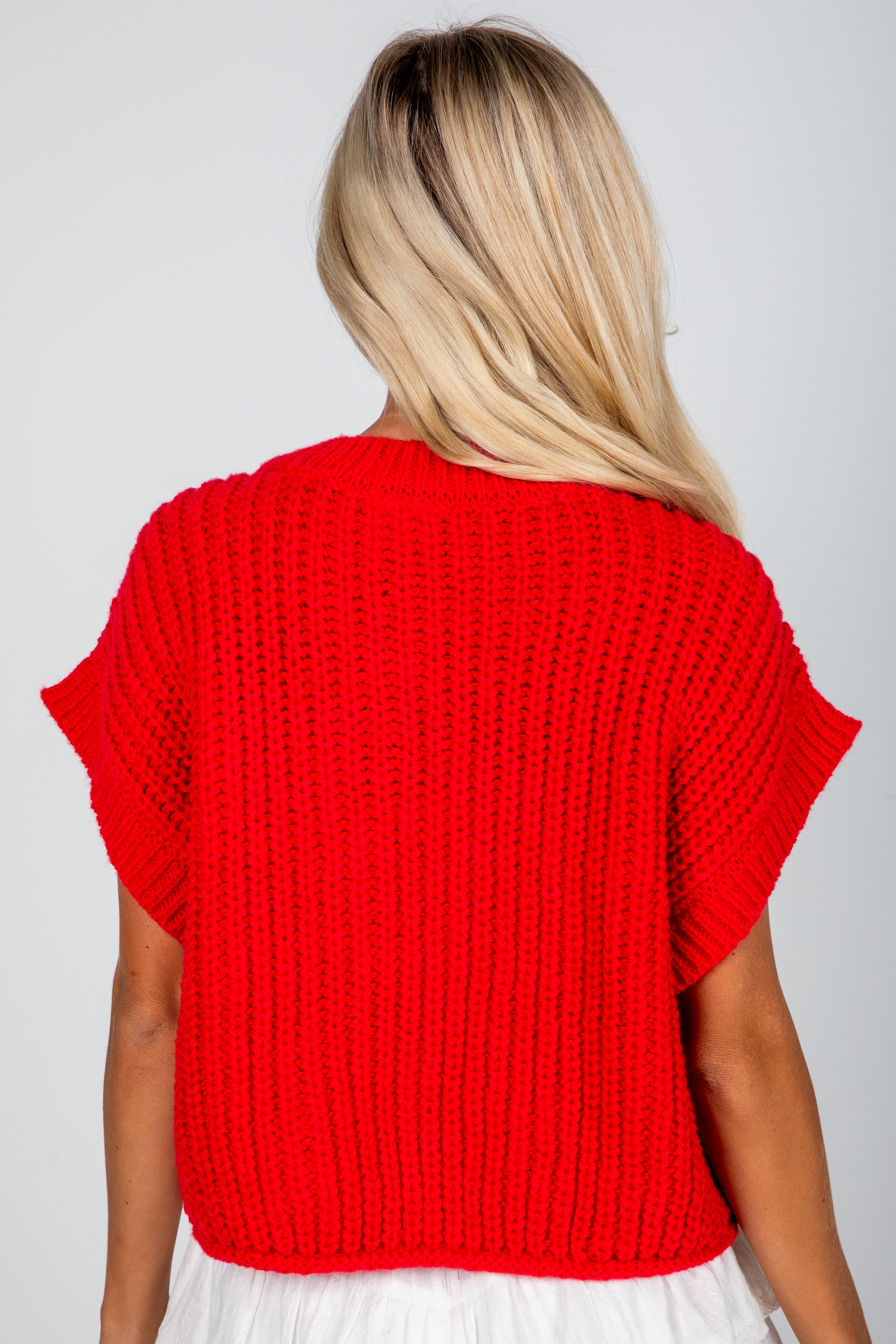 Person wearing a red knitted top on a plain background