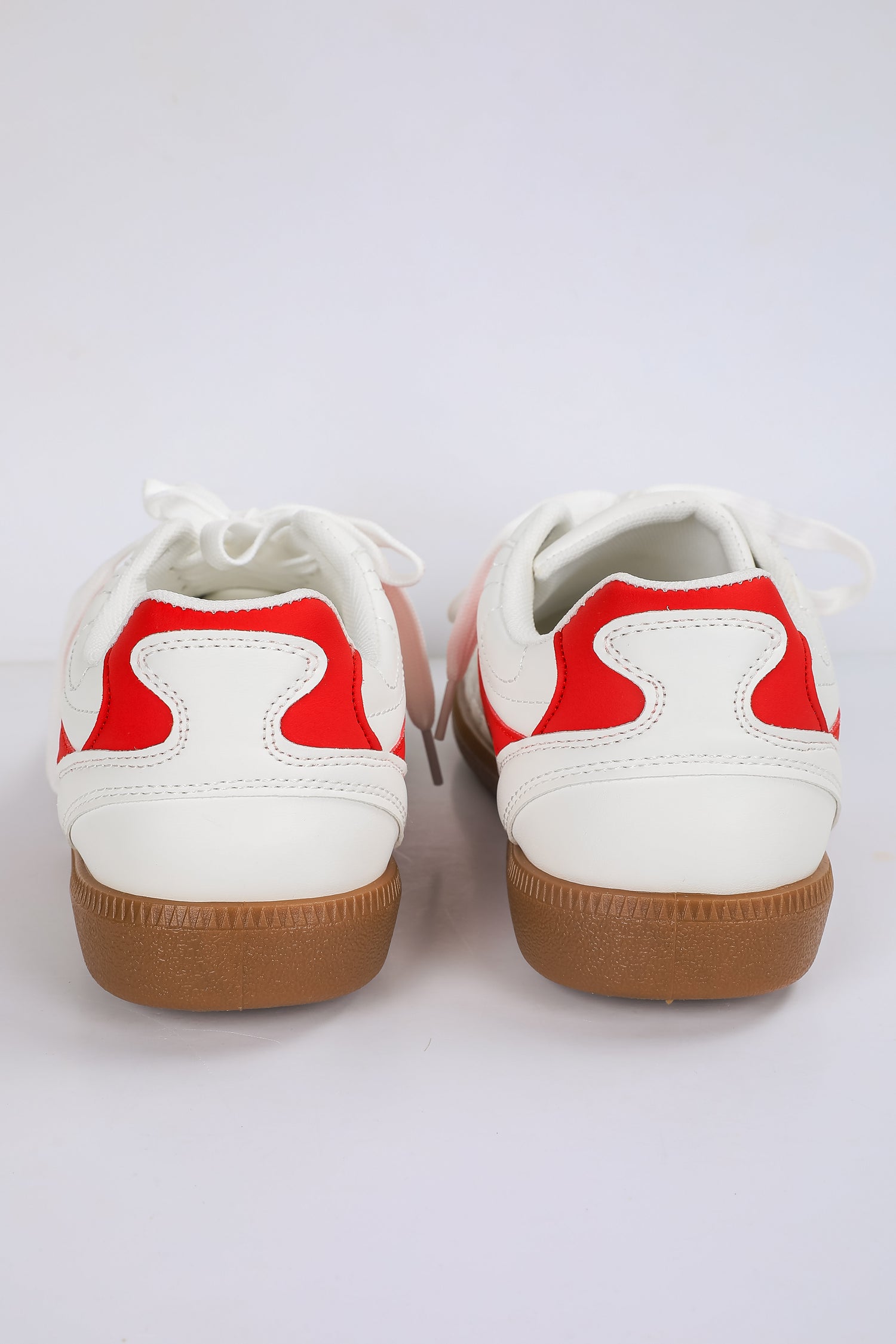 White sneakers with red accents and brown soles on a white background