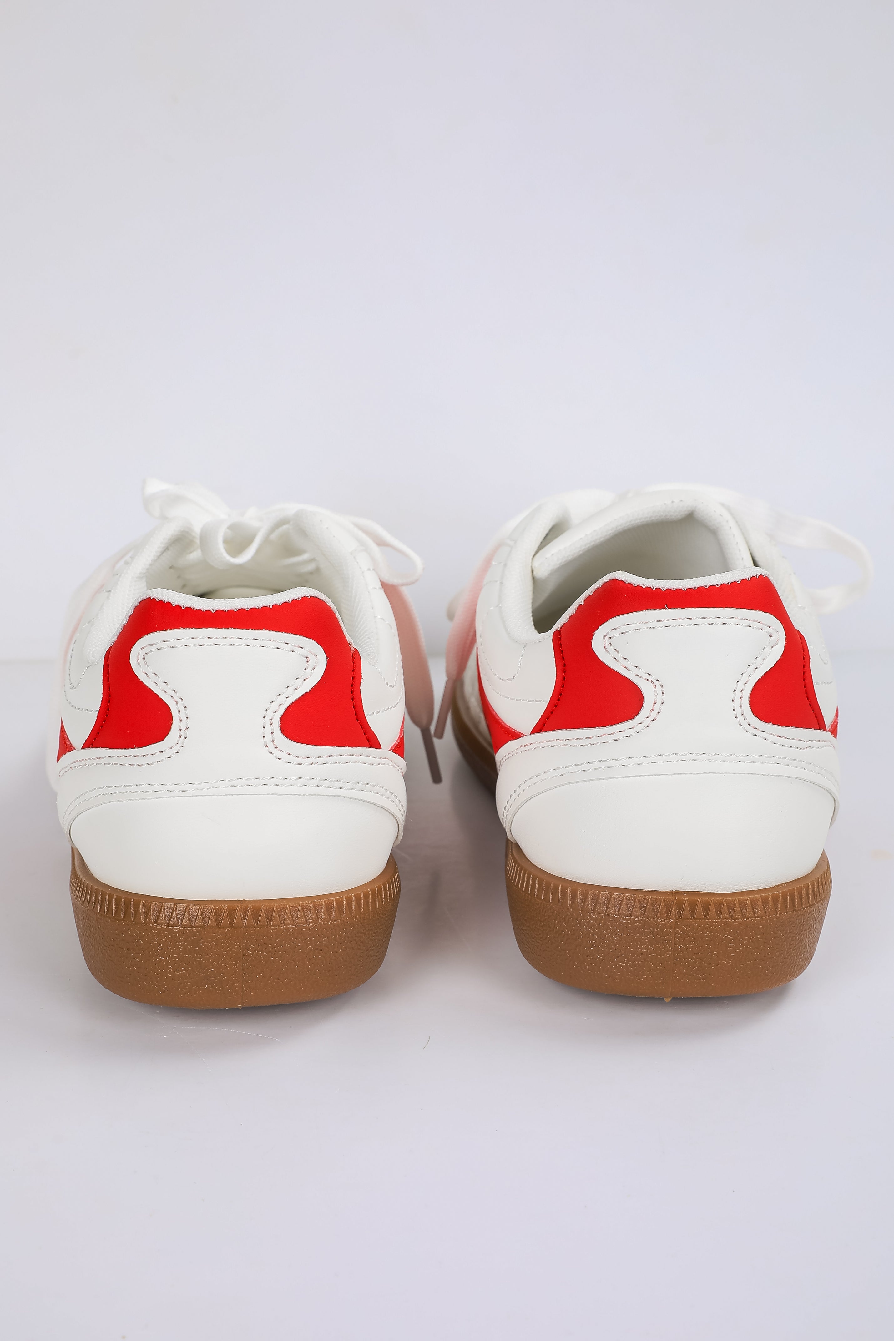 White sneakers with red accents and brown soles on a white background