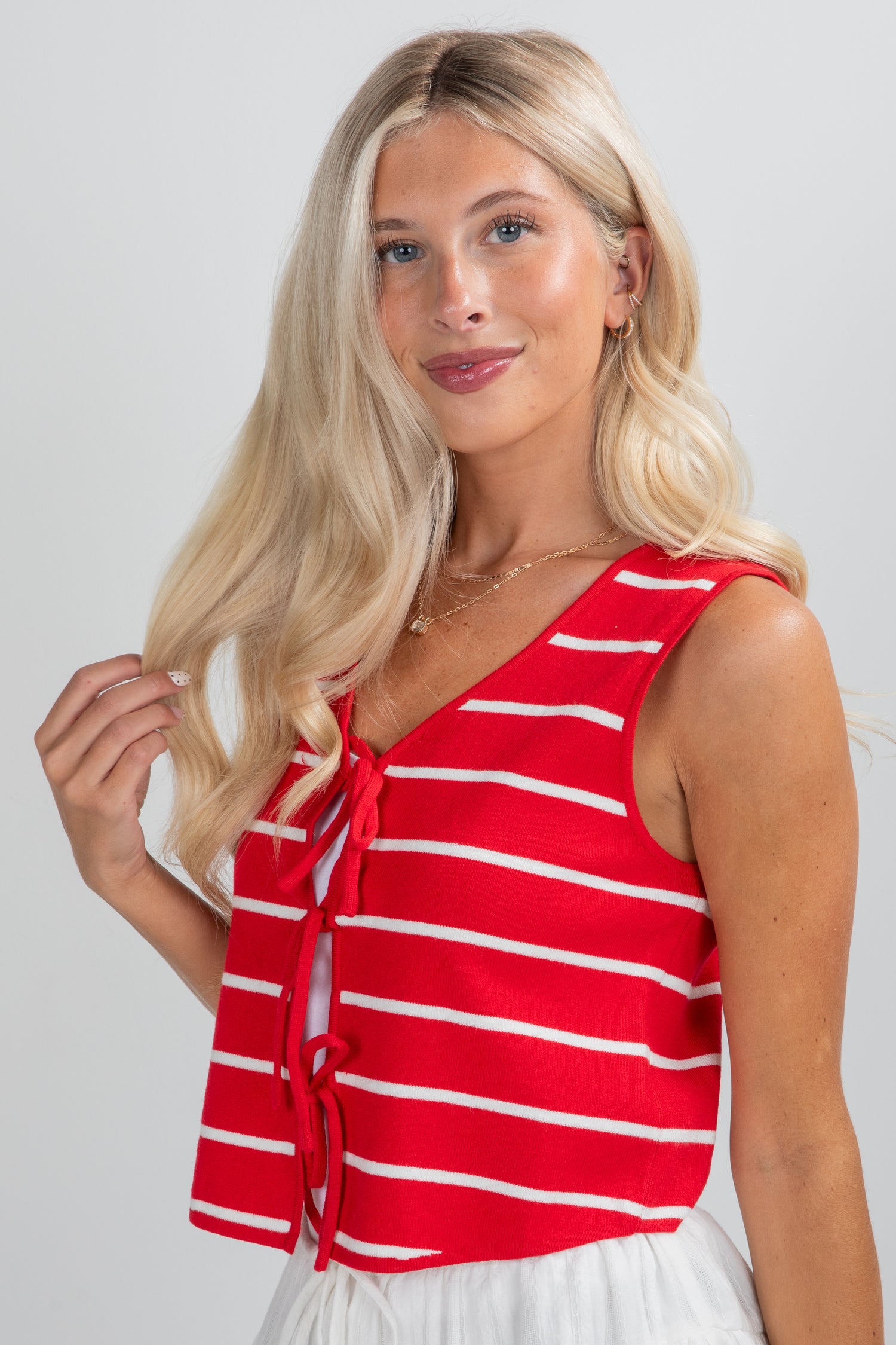 Woman wearing a red and white striped sleeveless top against a plain background
