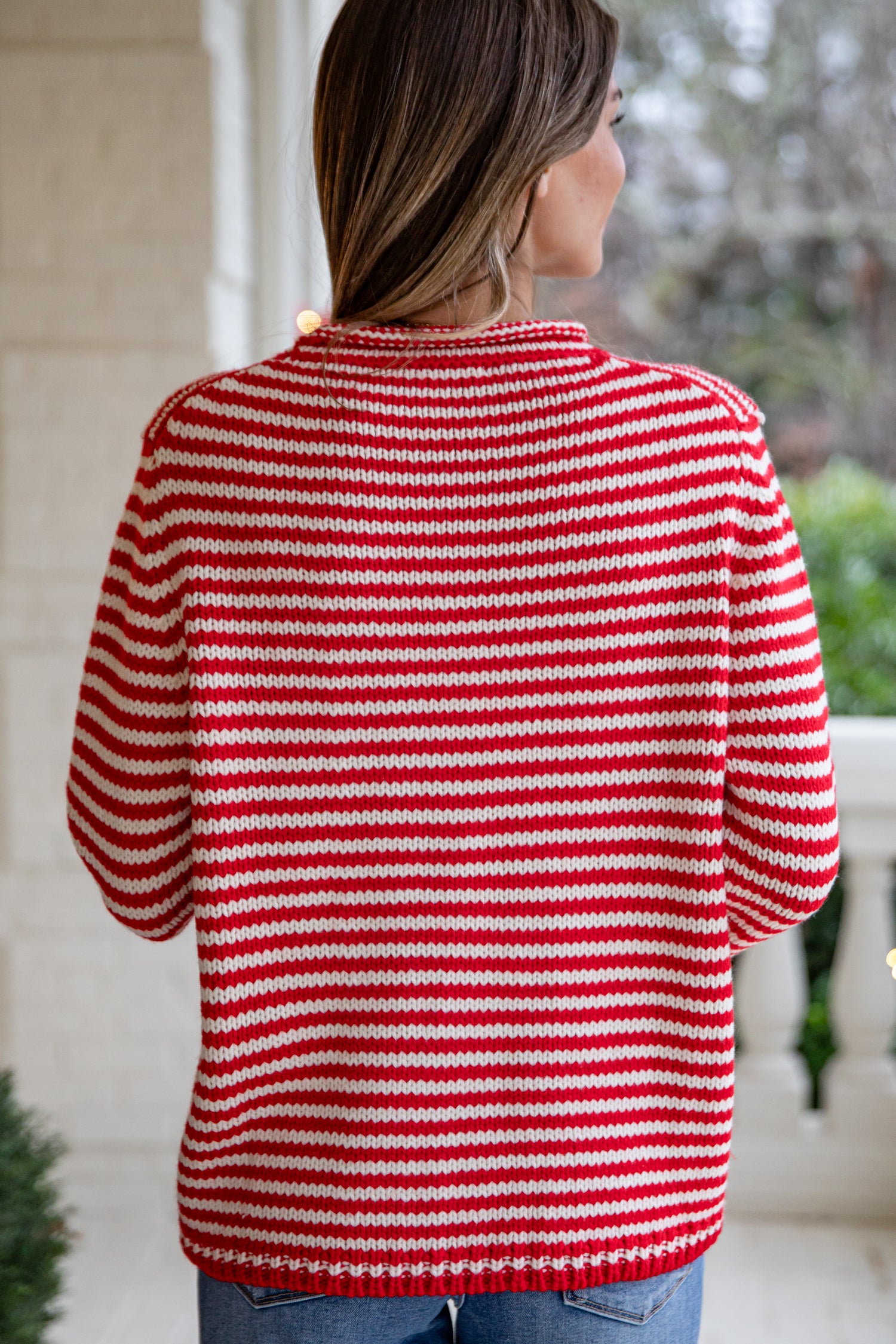Person wearing a red and white striped sweater outdoors.