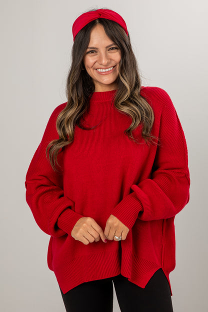 Woman wearing a red sweater and headband against a plain background