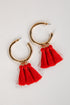 Gold hoop earrings with red tassels on a light gray background