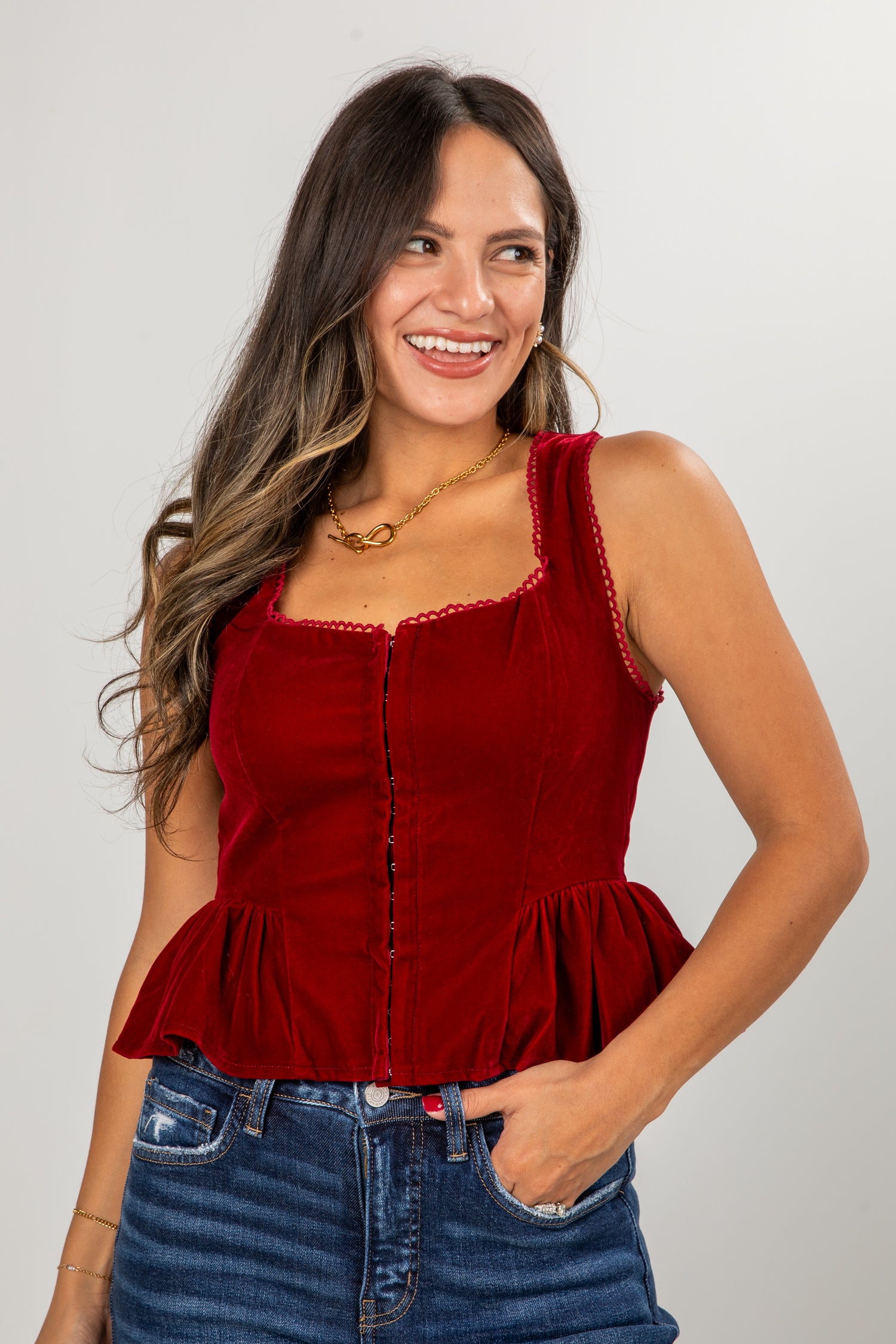Woman wearing a red peplum top and blue jeans against a plain background